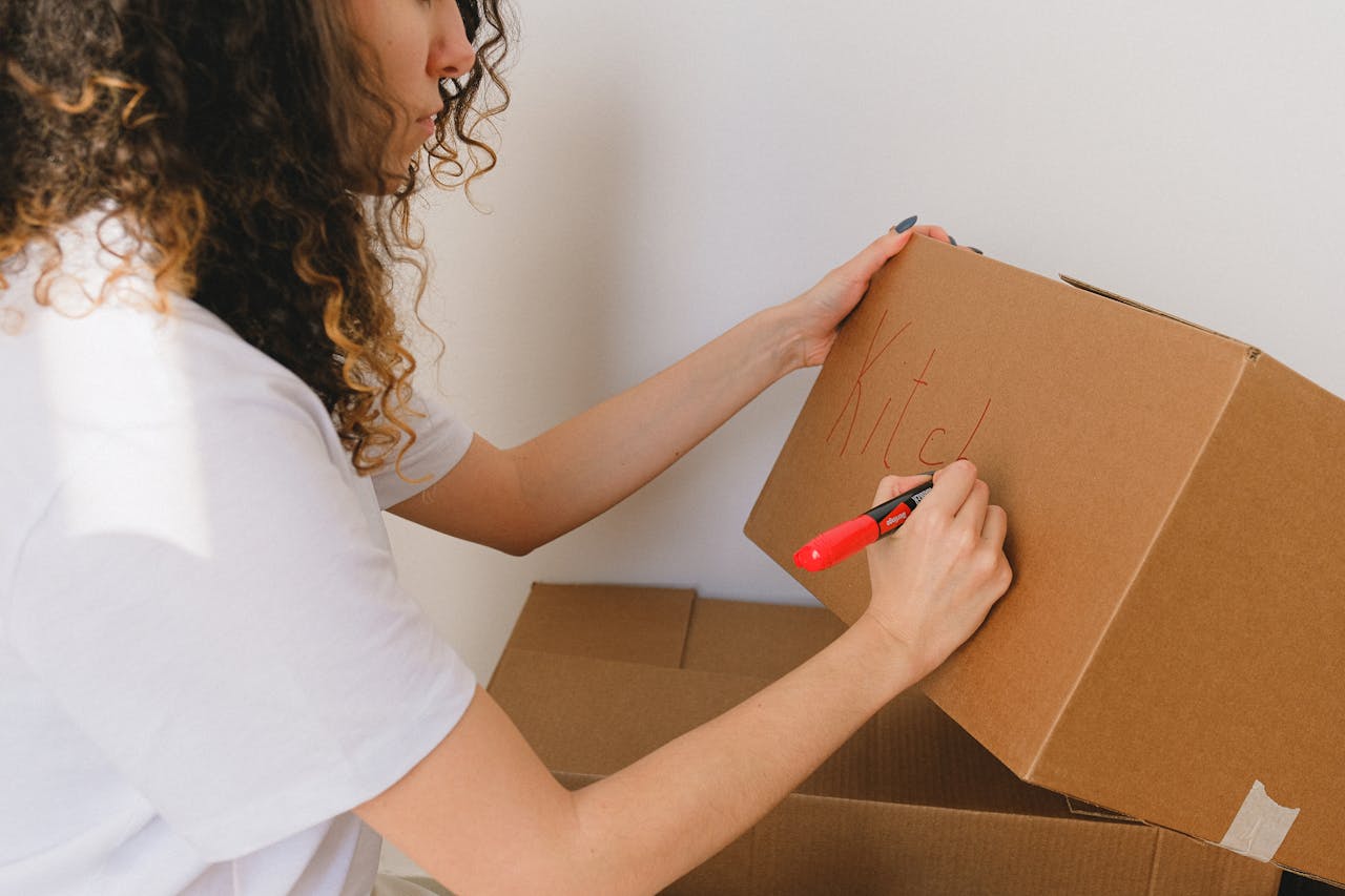 stats-img Woman organizing and labeling cardboard boxes for moving indoors.